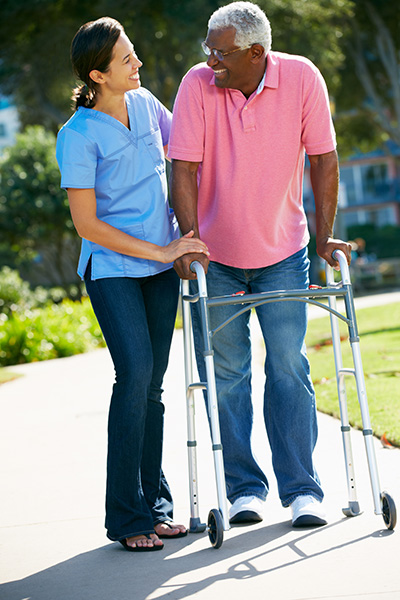 Carer Helping Senior Man With Walking Frame